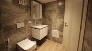 A modern bathroom with a marble wall, a sink, a mirror, and a toilet. - Duplex City 01 in Durr s (Durrës)