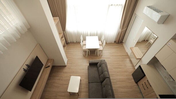 A modern living room with a sofa, a coffee table, and a TV. There is a dining area with a table and chairs. The room has wooden flooring and light-colored walls. - Duplex City 01 in Durr s (Durrës)