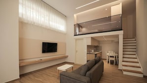 A modern apartment with a living room, a sofa, a TV, a staircase, and a kitchen area. - Duplex City 08 in Durr s (Durrës)