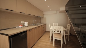 A modern kitchen with wooden cabinets, a dishwasher, and a dining area with white chairs. - Duplex City 08 in Durr s (Durrës)