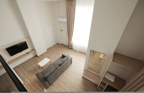 A modern living room with a grey sofa, a flat-screen TV, a small white table, and a wooden floor. - Duplex City 04 in Durr s (Durrës)