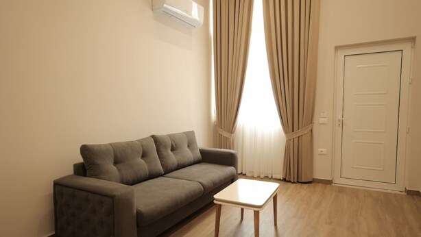 Ein modernes Wohnzimmer mit einem grauen Sofa, einem kleinen weißen Tisch und einer Tür.