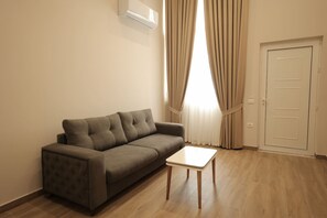 Ein modernes Wohnzimmer mit einem grauen Sofa, einem kleinen weißen Tisch und einer Tür.