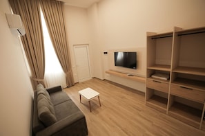 A modern living room with a sofa, a coffee table, a TV on a wooden shelf, and a wardrobe. - Duplex City 02 in Durr s (Durrës)