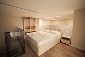 Ein modernes Schlafzimmer mit einem großen Bett, Nachttischen, einem Kleiderschrank und einer Glastrennwand.