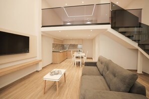 Un appartement moderne comprenant un salon, une cuisine et un escalier doté de rampes en verre.