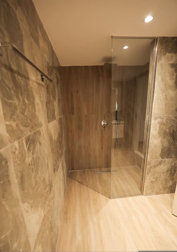 A modern shower with glass doors, a wooden wall, and a light-colored floor. - Duplex City 03 in Durr s (Durrës)