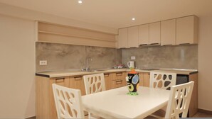 A modern kitchen with a white table and chairs, a sink, and cabinets. - Duplex City 03 in Durr s (Durrës)