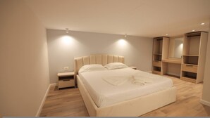 A bedroom with a bed, bedside tables, a wardrobe, and built-in shelving. - Duplex City 03 in Durr s (Durrës)
