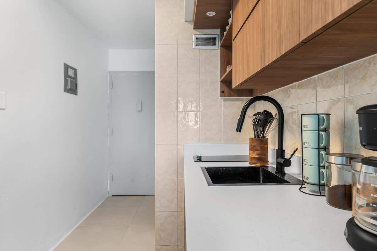 A modern kitchen with a white countertop, a black faucet, and a coffee machine.
