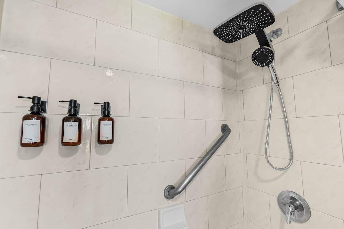 Un espace douche équipé d’un pommeau de douche à main, d’un flexible de douche et d’un autre flexible de douche.