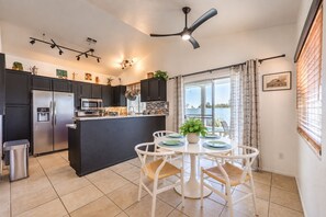 A modern kitchen with a central island, black cabinets, stainless steel appliances, and a dining area with white chairs and a table. - Vegas Designer Private Pool Oasis, King Suite, BBQ (Las Vegas)