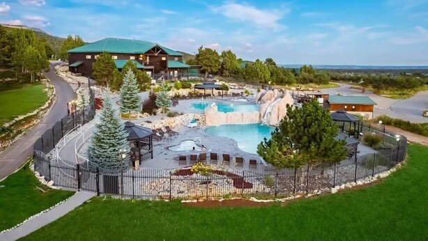 Un resort con una amplia piscina al aire libre, un jacuzzi y una cascada.