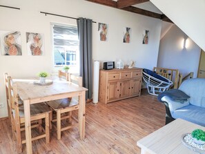 Ein gemütliches Zimmer mit einem Holztisch, einer Couch, einem Schrank und Bildern an der Wand.
