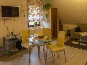 A living room with a glass table, yellow chairs, a sofa, a TV, and a window with floral curtains. - mit Fasssauna by Interhome (Bautzen)