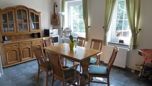A dining area with a wooden table and chairs, a cabinet with glass doors, and a guitar on the wall. - Bergblick by Interhome (Sehmatal)