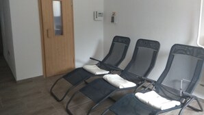 A room with a wooden door, a thermostat, and three reclining chairs with cushions. - Bergblick by Interhome (Sehmatal)