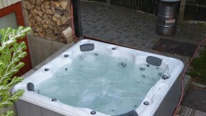 A hot tub with a stone wall and a wooden deck in the background. - Bergblick by Interhome (Sehmatal)