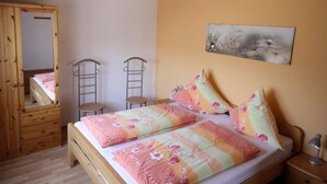 Ein Schlafzimmer mit einem hölzernen Bett, zwei Stühlen, einem Schminktisch und einem Gemälde an der Wand.