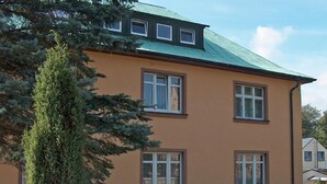 Ein zweistöckiges Gebäude mit einem grünen Dach und zahlreichen Fenstern.