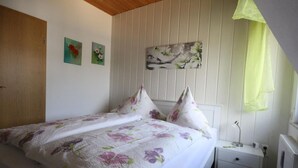 Un dormitorio con cama, mesita de noche, un cuadro colgado en la pared y una puerta.