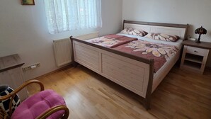 A bedroom with a wooden bed, a bedside table with a lamp, a chair, and a window with sheer curtains. - 2 Raum  Graal-Müritz by Interhome (Graal Müritz)