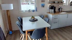 A compact kitchen with a dining area, a window with a view of a canal, and a small potted plant on the table. - Hausboot Tosca by Interhome (Stralsund)