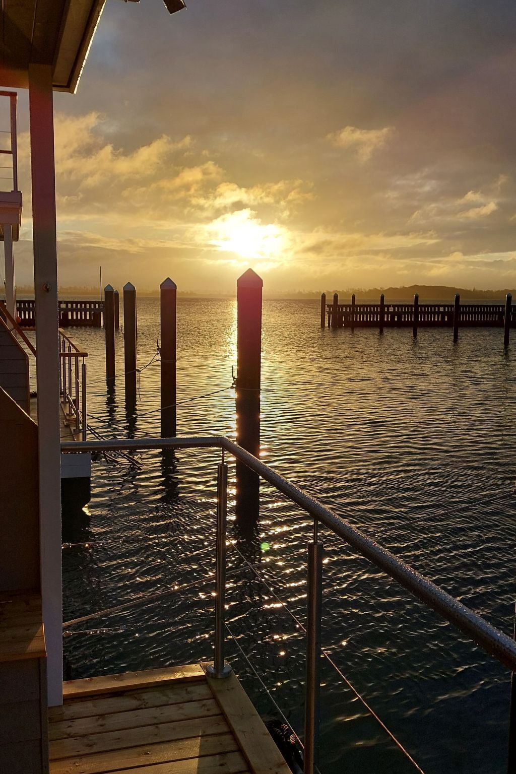 Un muelle se adentra en aguas tranquilas, con un atardecer al fondo.