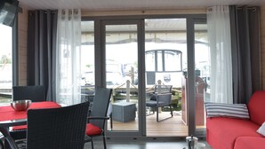 A room with a dining area, a sofa, and a view of the outside. - Hausboot NautikHus by Interhome (Werder (Havel))