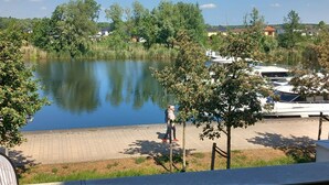 Een uitzicht over het meer met een steiger en boten, omringd door bomen en huizen.