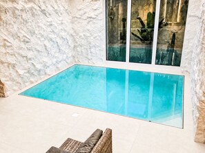 An indoor swimming pool with a clear blue water surface, surrounded by a textured white wall and a glass window. - UG Neubau City by Interhome (Munich)