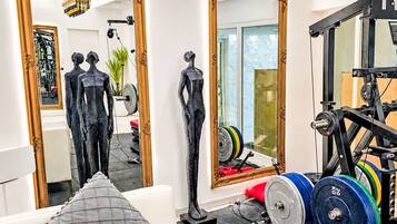 Ein Fitnessraum mit Trainingsgeräten, einem Spiegel und zwei Statuen.