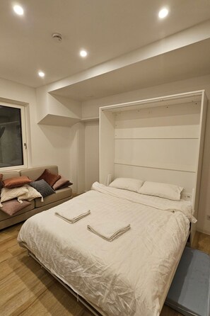 Een slaapkamer met een groot bed, een bank en een raam.
