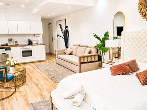 A modern bedroom with a large bed, a sofa, a dining table, and a kitchen area. - UG Neubau City by Interhome (Munich)