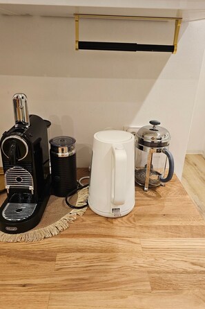 Een koffiezetapparaat, een waterkoker en een French press op een houten tafel.