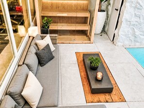 A modern outdoor living area with a sofa, cushions, a coffee table, and a small plant. - UG Neubau City by Interhome (Munich)
