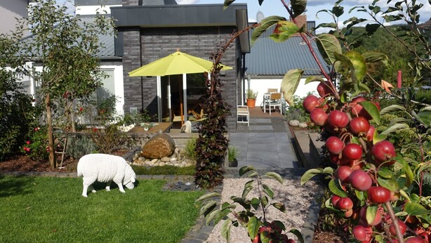 Een modern huis met een verzorgde tuin, gazon en een pad dat naar de ingang leidt.