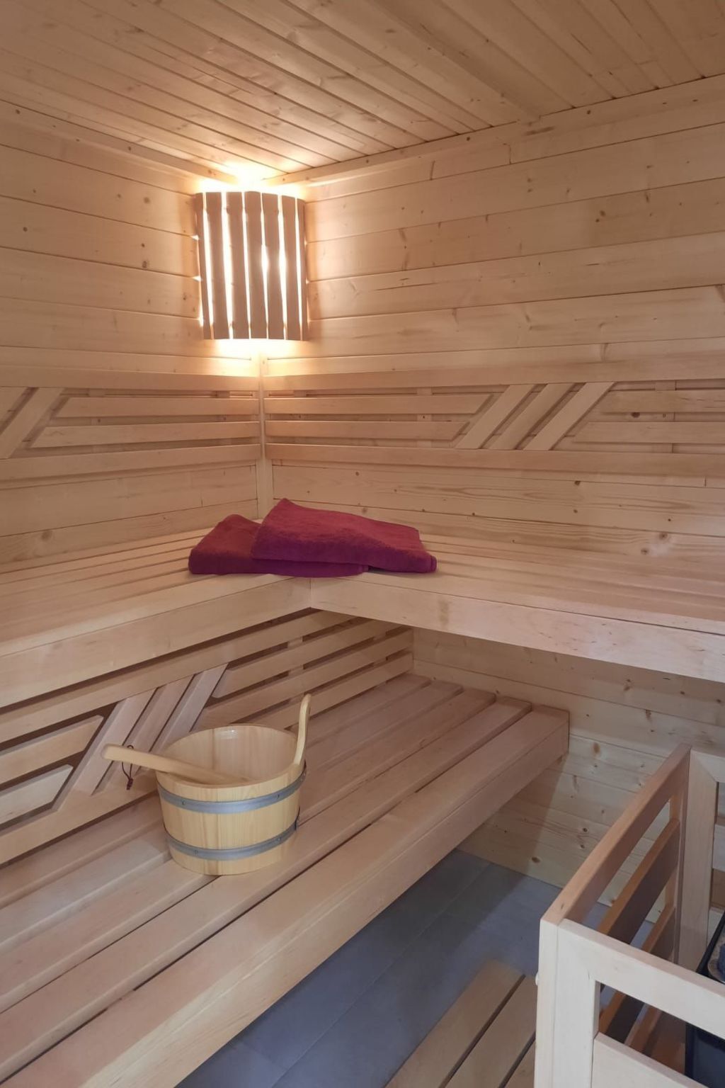 Una sauna amb grans de fusta, bancs de fusta i un cubell de fusta.