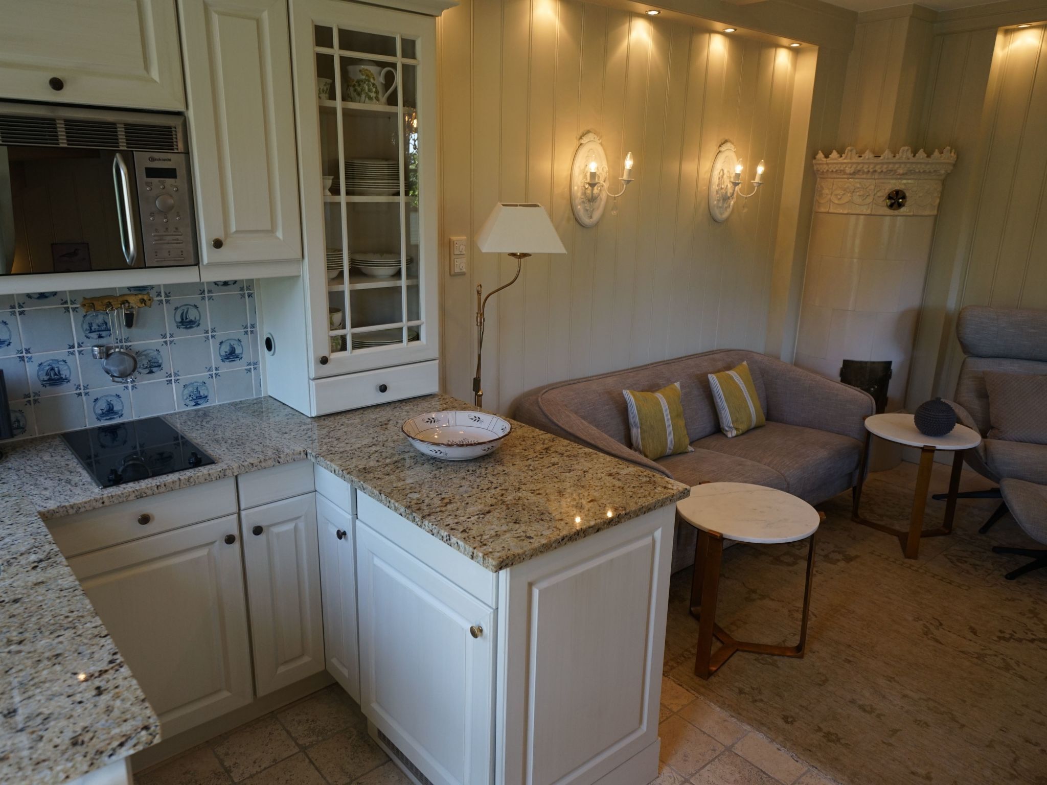 A kitchen with white cabinets, a granite countertop, a built-in stove, and a glass-fronted cabinet with dishes.