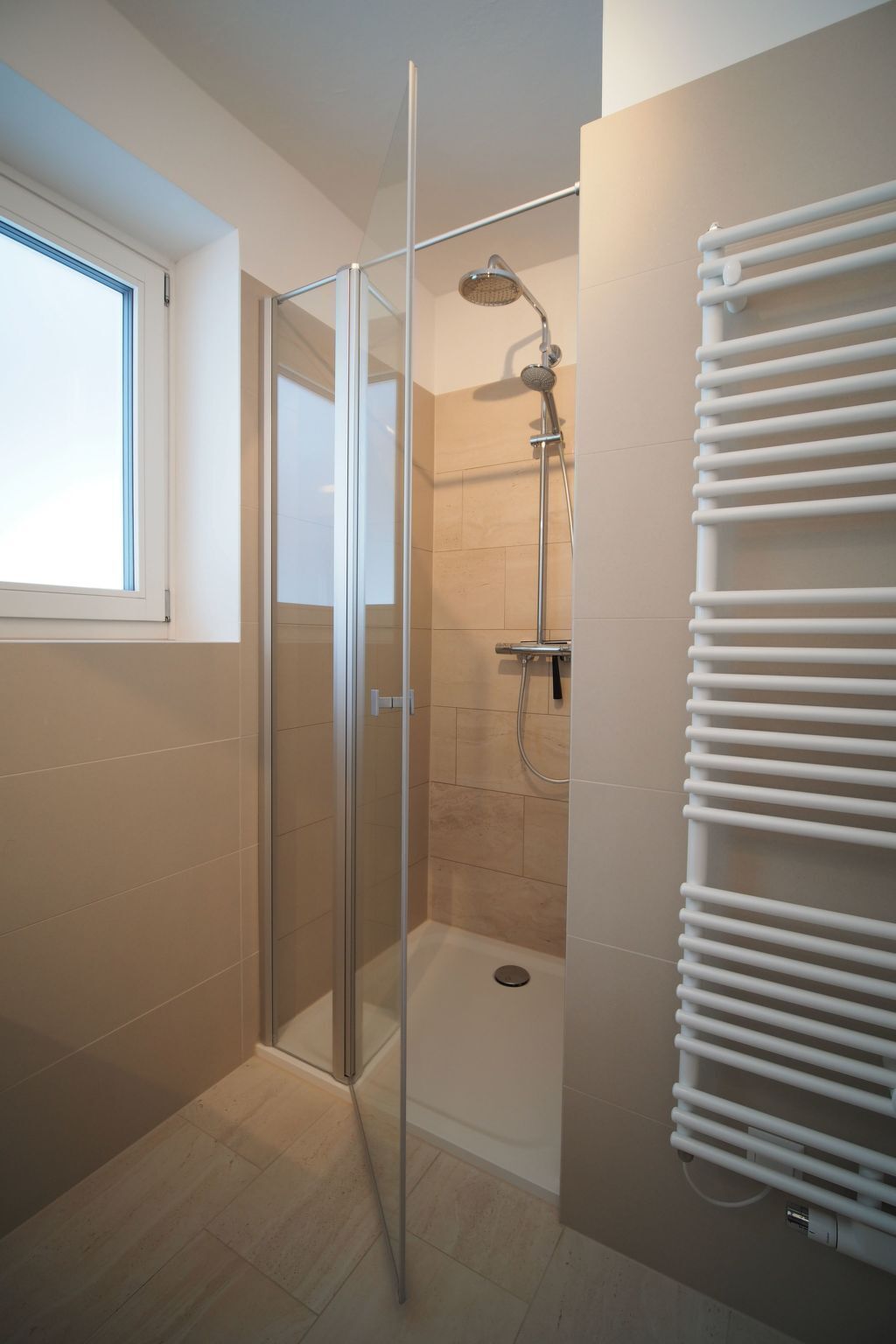 A modern bathroom with a glass shower enclosure, a built-in toilet, and a wall-mounted towel rack.