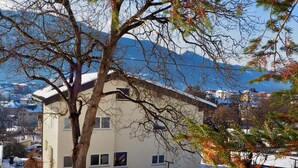 A two-story building with a snow-covered roof, surrounded by trees and a mountainous backdrop. - Haus an der Lieser by Interhome (Spittal an der Drau)