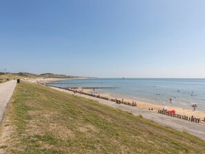 A coastal beach with a paved walkway, sandy beach, and a clear view of the sea. - Studio Appartement by Interhome (Zoutelande)