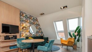 Ett modernt vardagsrum med en TV, en soffa, ett runt bord och stolar.