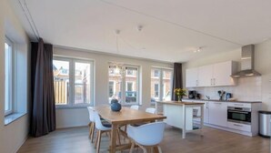 Une cuisine moderne avec des meubles blancs, une table à manger en bois et un four encastré.