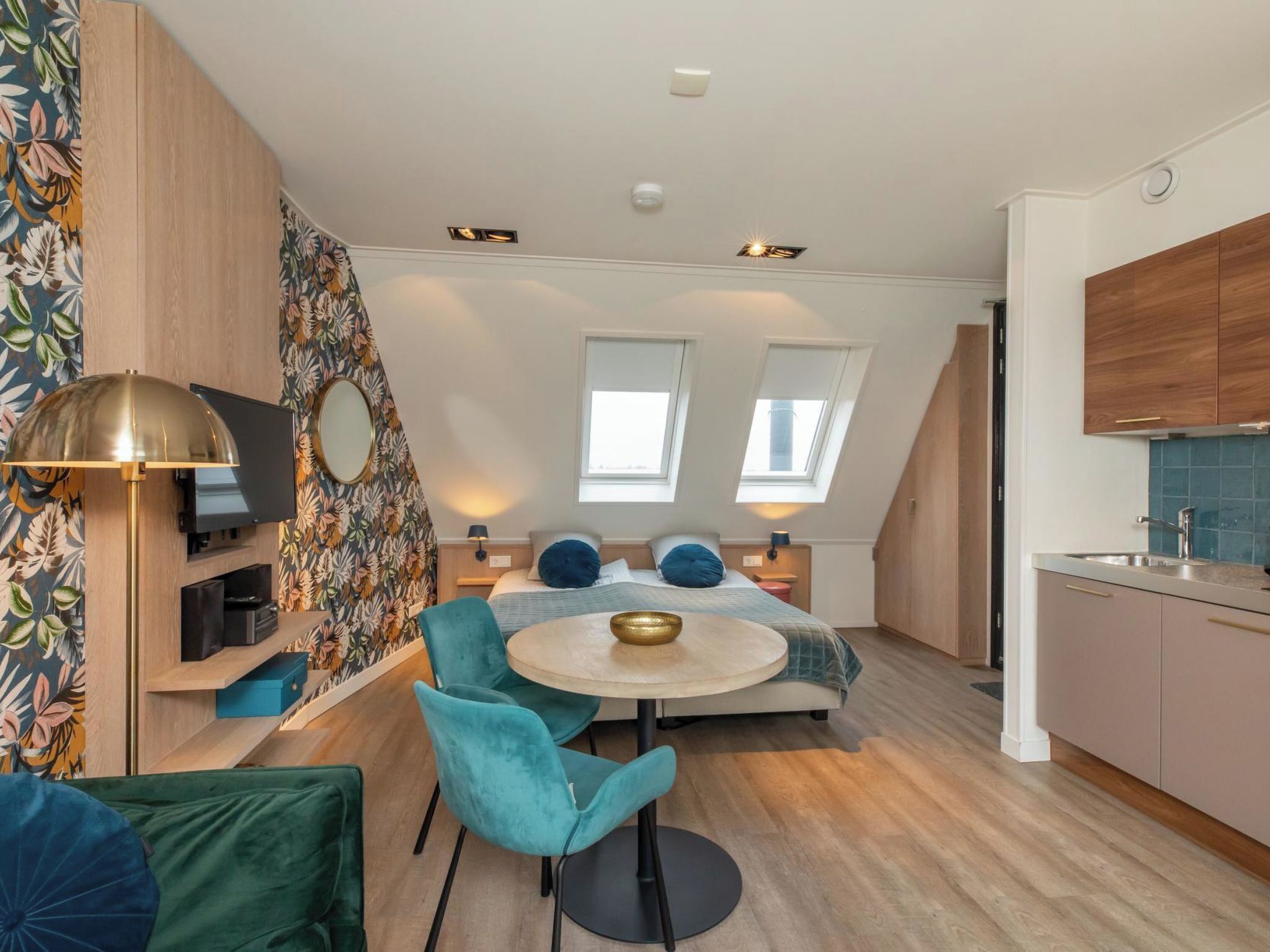 Eine kompakte, moderne Wohnung mit einer Küchenzeile, einem Essbereich und einem Schlafzimmer mit Dachfenstern.