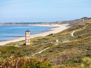 A coastal landscape with a lighthouse, beach, and hilly terrain. - Duinzand Sauna E by Interhome (Koudekerke)