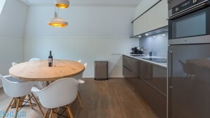 Eine moderne Küche mit einem runden Holztisch, weißen Stühlen und Pendelleuchten.