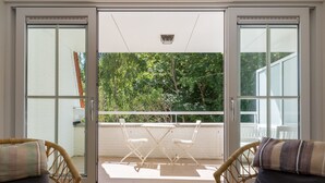 Ein Zimmer mit einer Schiebetür aus Glas, die auf einen Balkon mit Tisch und Stühlen führt.