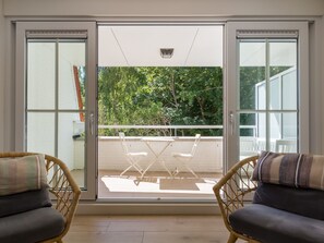 Ein Zimmer mit einer Schiebetür aus Glas, die auf einen Balkon mit Tisch und Stühlen führt.