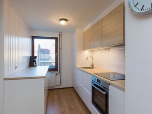 A modern kitchen with a built-in oven, a sink, and a window with blinds. - Vestingsplek by Interhome (Veere)